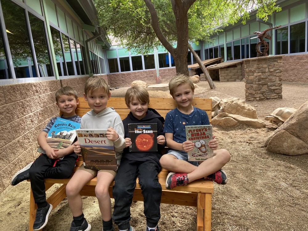 Four students sitting on a bench in the Tortoise Habitat.
