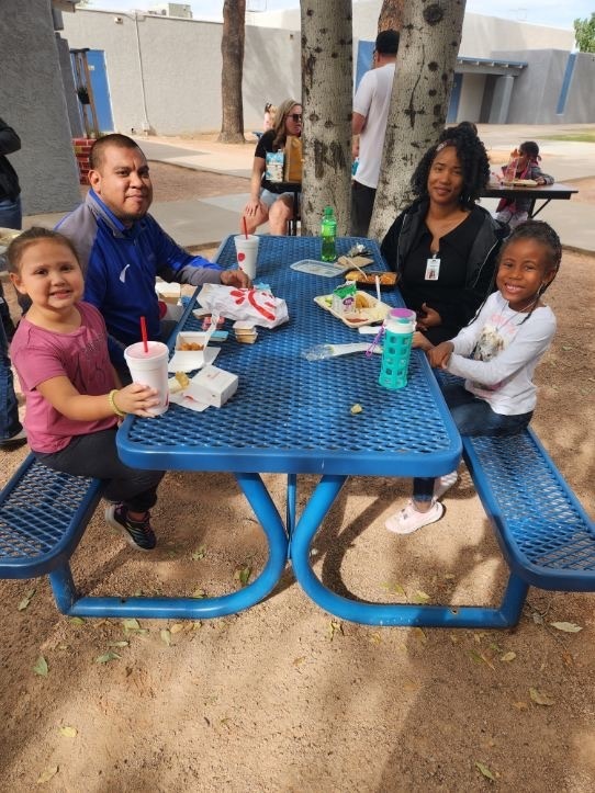 Families eating lunch outside on blue benches