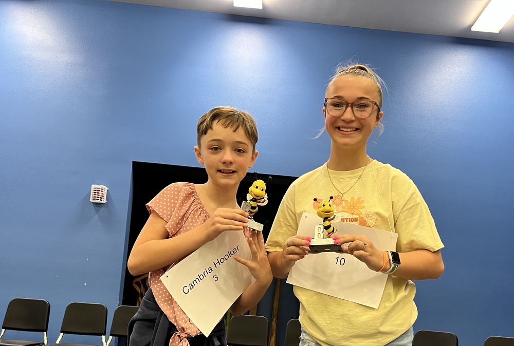Cami and Sophie holding their Spelling Bee trophies.